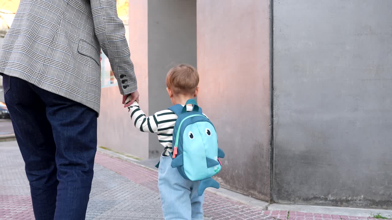 Adult and Child Holding Hands While Walking on City Street