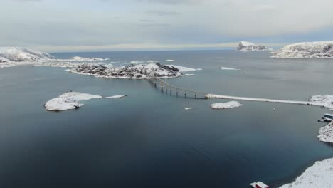 drone view in tromso area in winter flying over snowy islands with a large bridge flying towards its surrounded by the sea in norway