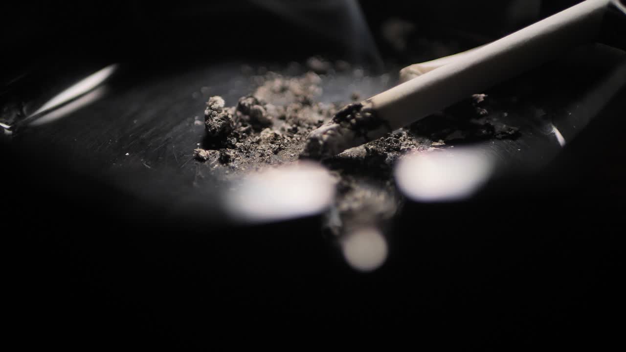 Close up smoking cigarette on man hand.Black ashtray. Scene C
