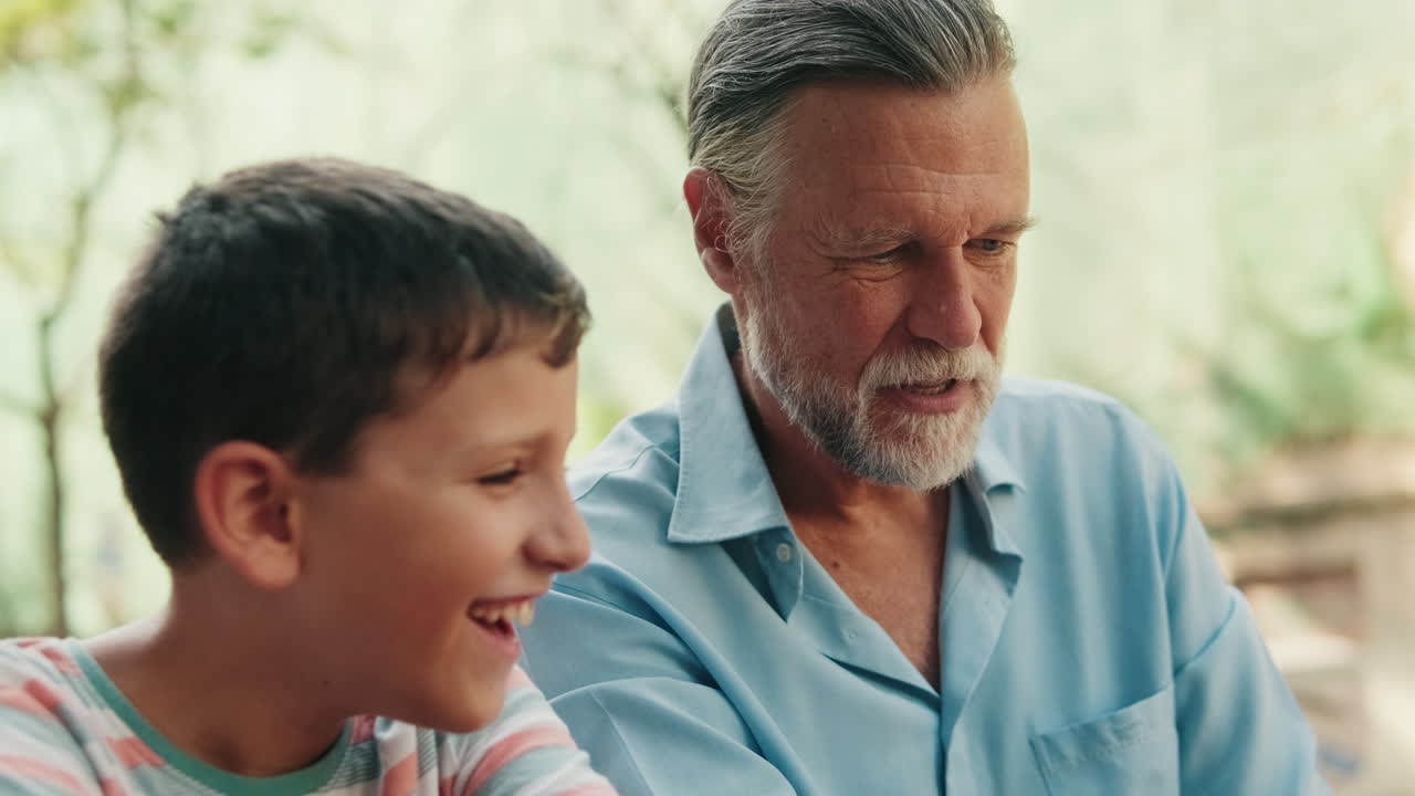 Happy Grandfather and Grandson Talking and Smiling Outdoors