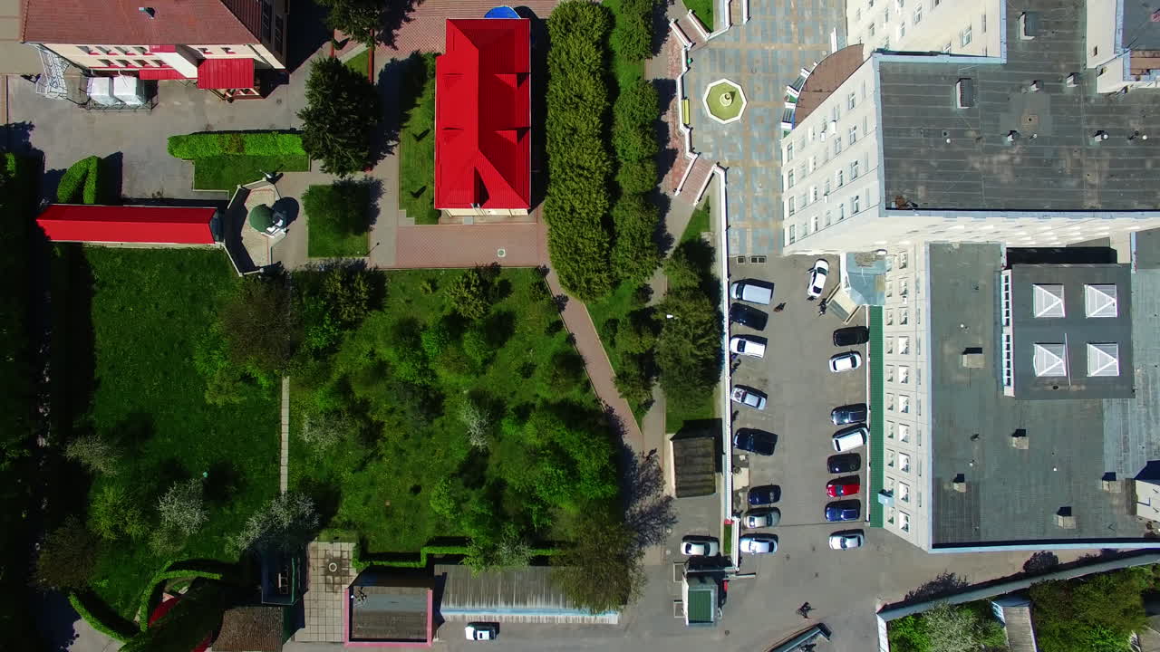 Descending over the residential area with beautiful well-kept territory. Drone footage over the building tops on sunny day.