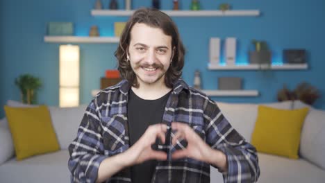 the man is making a heart against the camera. he's sending a kiss.