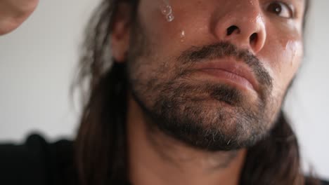 close-up of a man applying skincare product to his face with a dropper