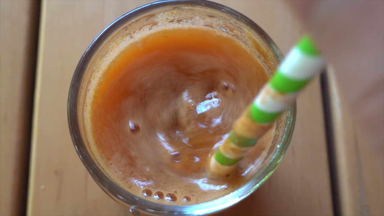 Uomo che mescola un succo di carota e mela con una cannuccia a strisce verdi e bianche