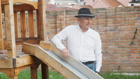 a tender moment between grandfather and grandson as they play together in a wooden playhouse with a slide in the backyard.