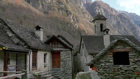 panning from the right to the left side of the frame, showing the stone houses of cavergno and the mountains behind it, in the district of vallemaggia, in the canton of ticino, in switzerland