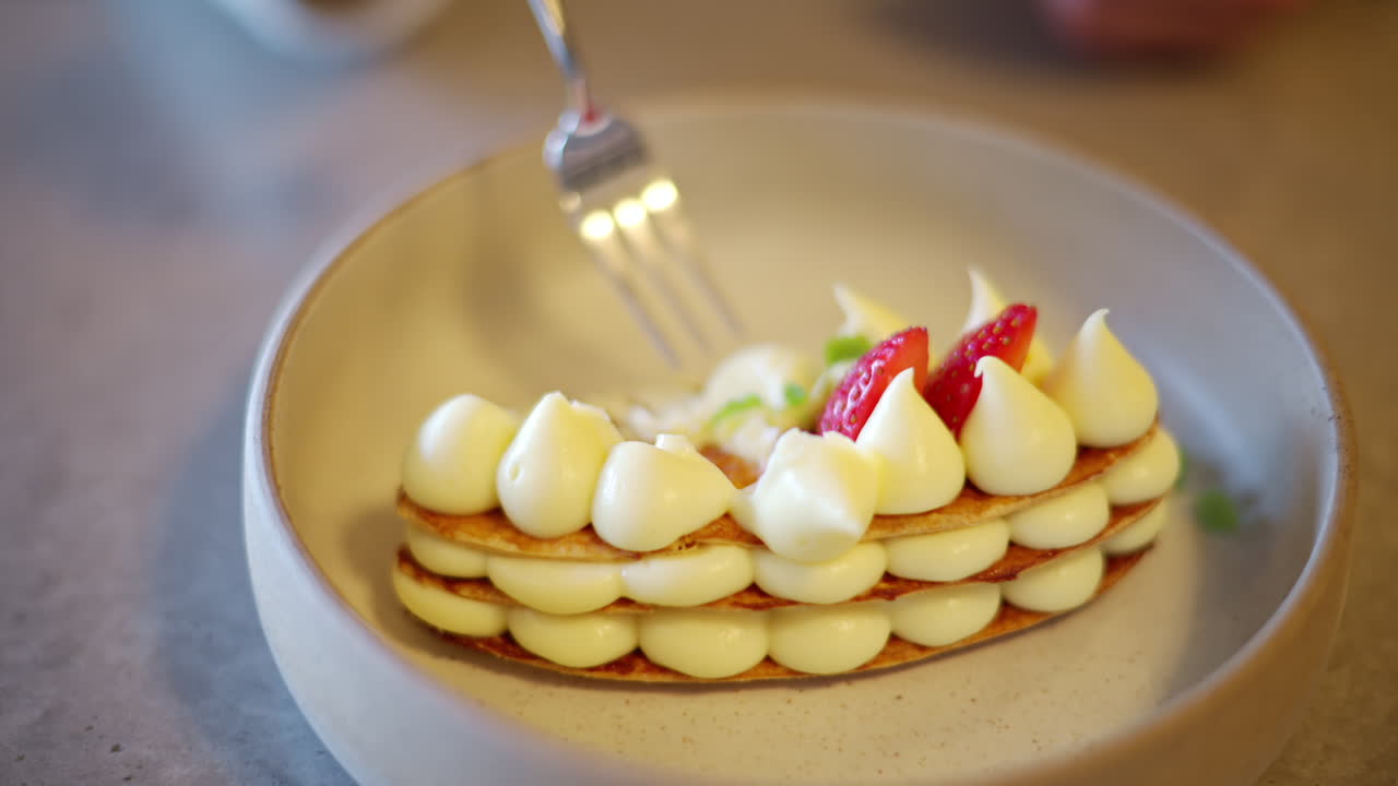 Woman eating Mille feuille cake with strawberry on a plate