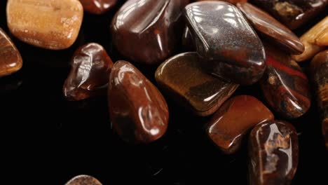 polished tiger's eye stones displayed on a black surface with warm lighting, highlighting their glossy texture and rich brown hues