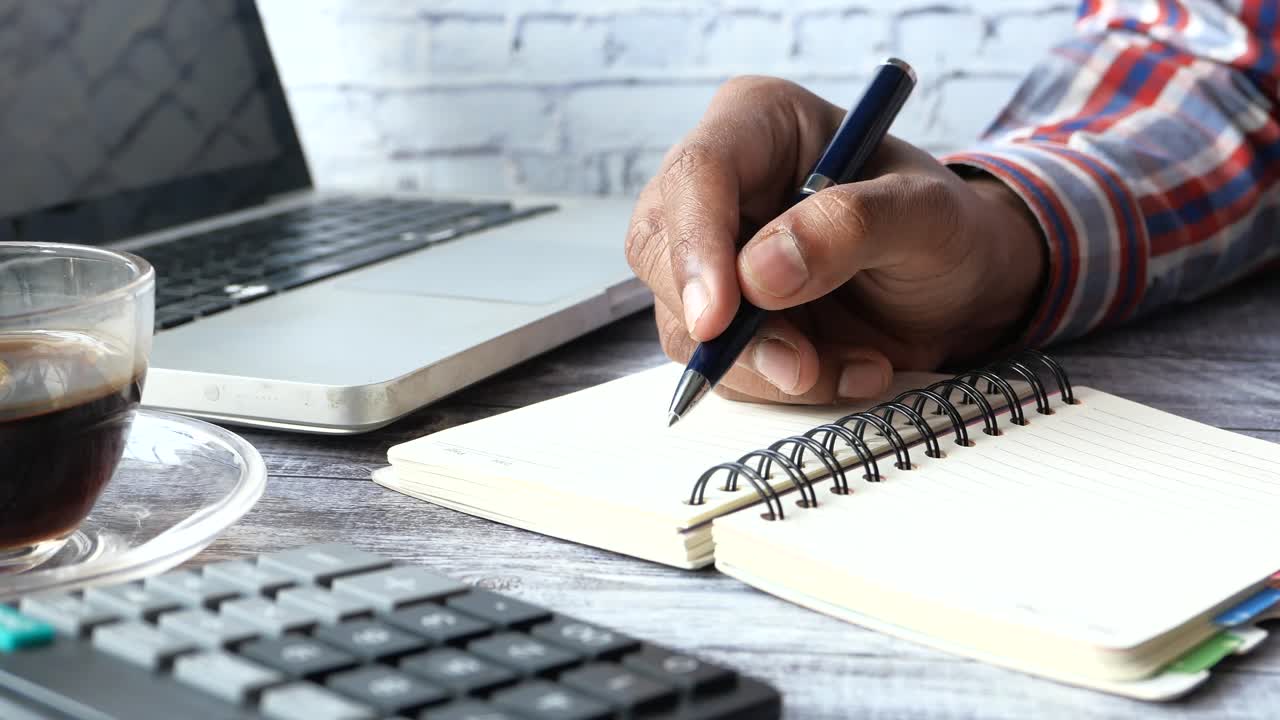persona escribiendo en un cuaderno en un escritorio