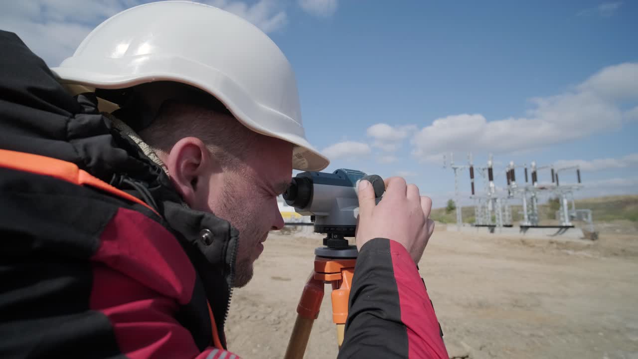 An engineer surveyor takes measurements at the construction of a transformer substation