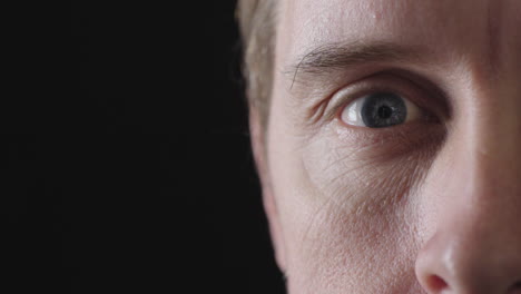 close-up-of-caucasian-man-blue-eye-looking-at-camera-smiling-happy-isolated-on-black-background-copy-space