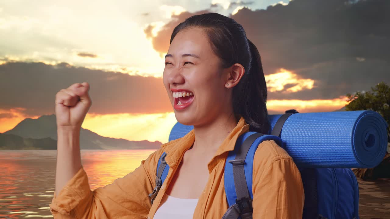 Close Up Side View Of Asian Female Hiker With Mountaineering Backpack Screaming Goal Celebrating The Success While Standing At A Lake During Sunset Time