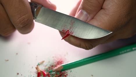 Footage-of-hands-slowly-sharpening-a-pencil-and-some-coloured-pencils-with-a-sharp-knife