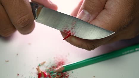 imágenes de manos afilando lentamente un lápiz y algunos lápices de colores con un cuchillo afilado