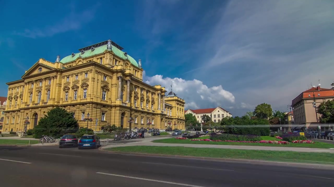 Bygningen af det Kroatiske Nationalteater, timelapse hyperlapse. Kroatien, Zagreb. Grøn plæne og trafik på vejen.