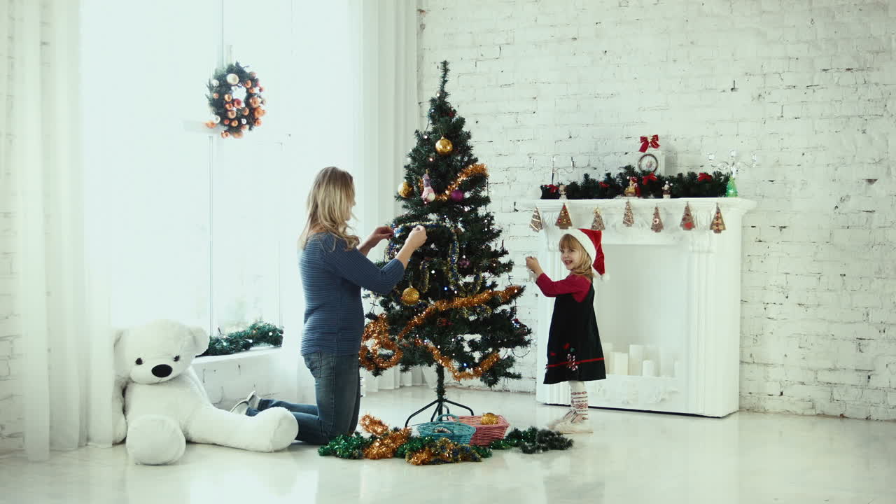 어머니 와 딸 이 크리스마스 트리 를 장식 하고 있다