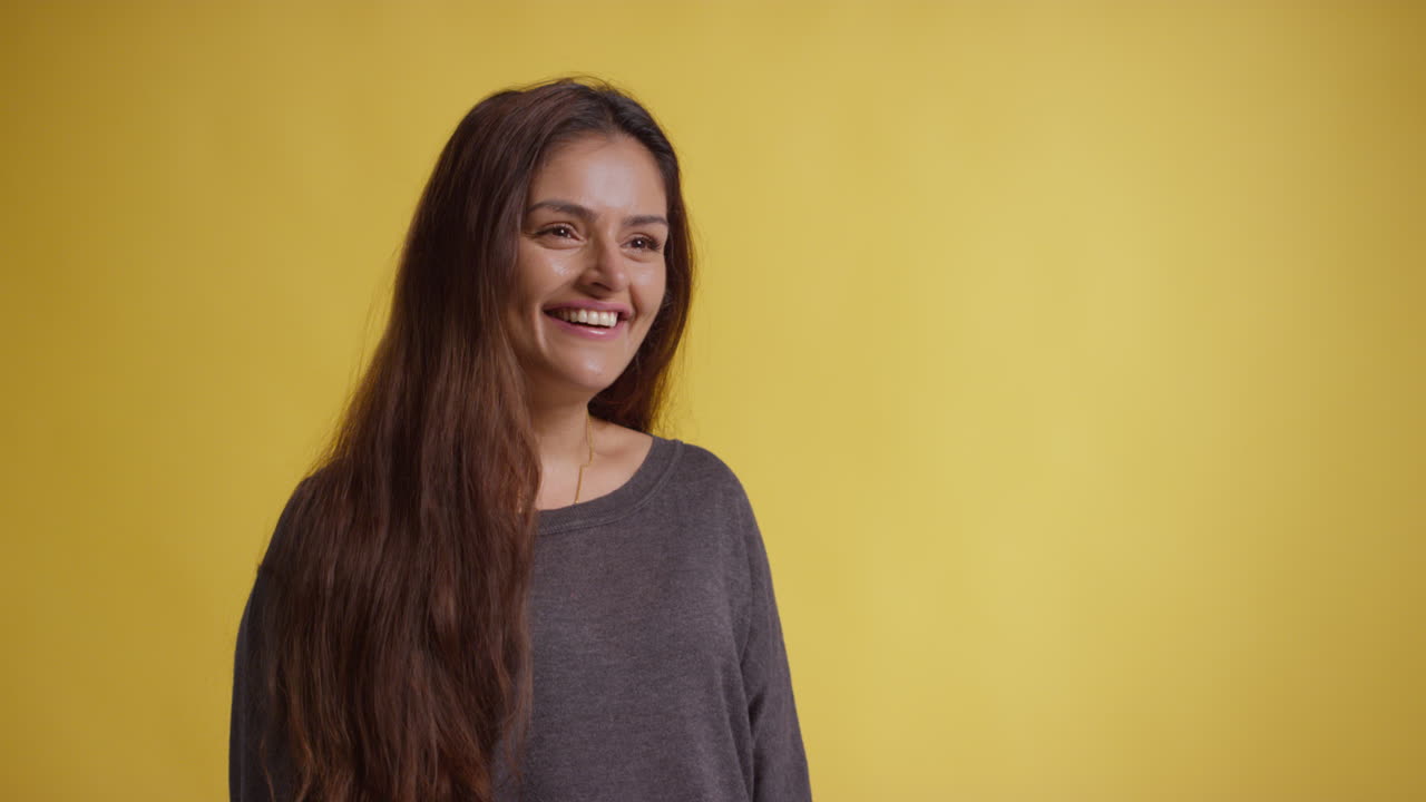 Head And Shoulders Studio Portrait Of Smiling Woman Against Yellow Background 3