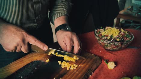 cerca de las manos del chef agregando pimiento verde a la ensalada.