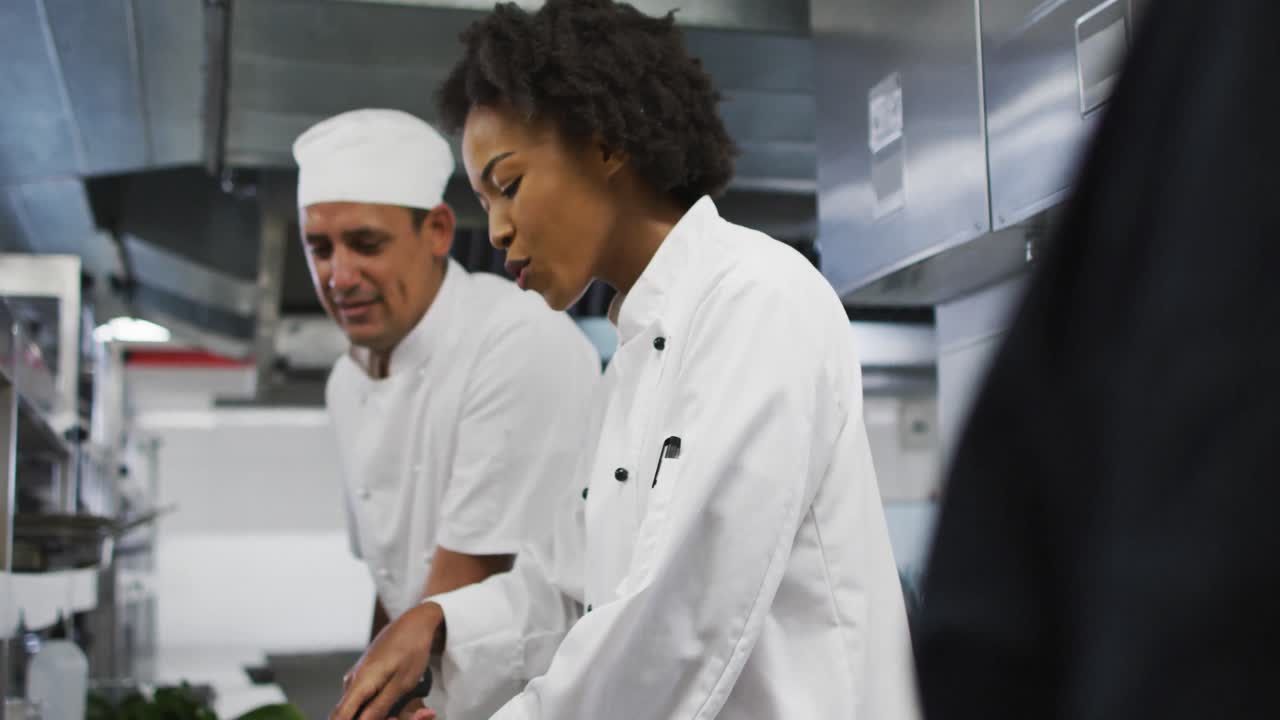 grupo diverso de chefs de pie alrededor de una mesa escuchando instrucciones