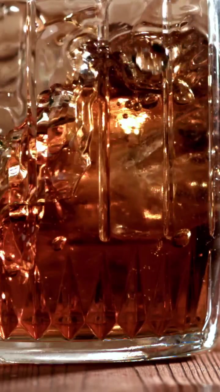 Cubetti di ghiaccio che schizzano in un bicchiere di whisky al rallentatore.