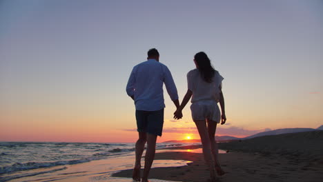 couple walking on beach at sunset