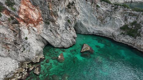 aerial pan of seaside cliffs and turquoise water at gjipe in albania