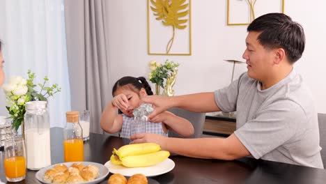 a father and daughter enjoy breakfast together in a bright, cozy dining room, sharing a playful moment while pouring water
