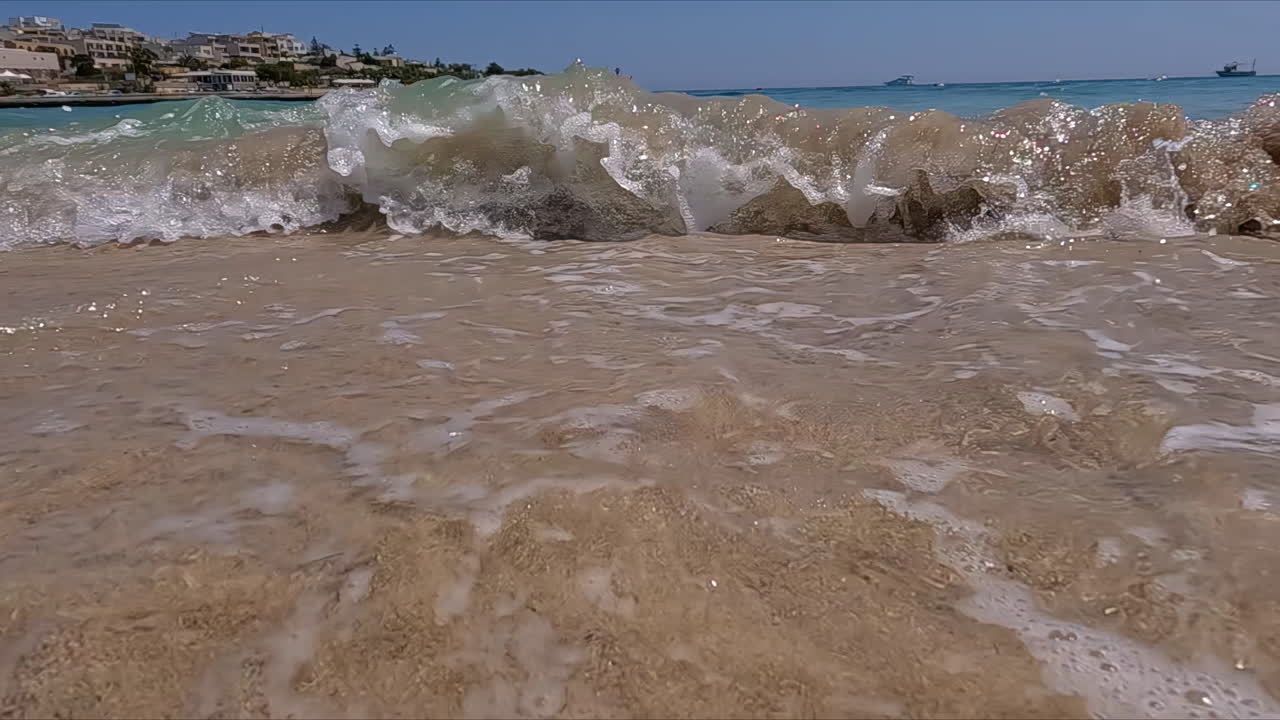 파란 바 ⁇ 물이 있는 멋진 해변의 클로즈업이 올라오고 파도가 카메라를 향해 부 ⁇ 히는 동안 천천히 움직이는 구름 없는 날의 멋진 관광 여름 여행