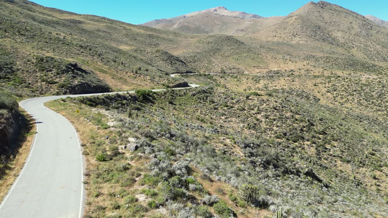 Aerial rises over road winding around hillside contours, Peru foothills