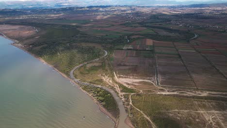 el río fluye a través de parcelas agrícolas y árboles forestales hacia el mar adriático en albania