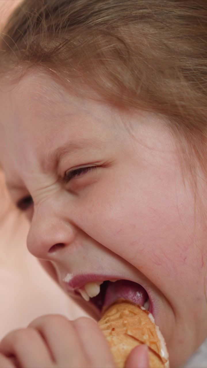 Close up of young girl eating ice cream cone with visible texture detail and soft lighting. background is softly blurred to emphasize subject focused expression as girl enjoys her treat