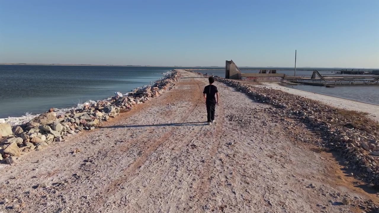En ung mand går alene på en støvet sti gennem de oversvømmede ruiner af Villa Epecuen i Argentina