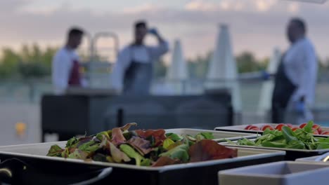 three young chefs preparing platters of gourmet salad outside the restaurant - close up shot