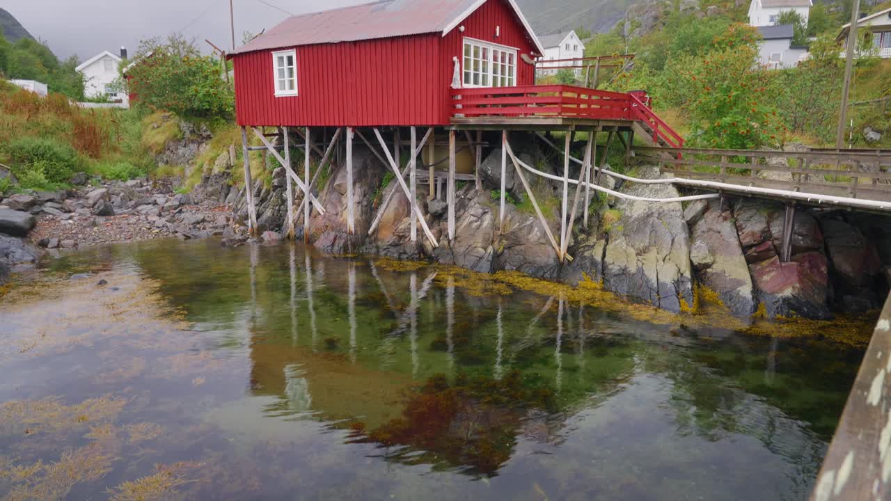 Tilt up reveal footage of the red rorbu houses in the beautiful fisher village of Å in the Lofoten Islands, Norway