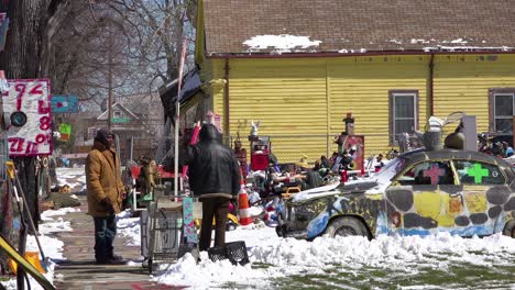 black men walk through a neighborhood in detroit filled with abandoned items and art objects