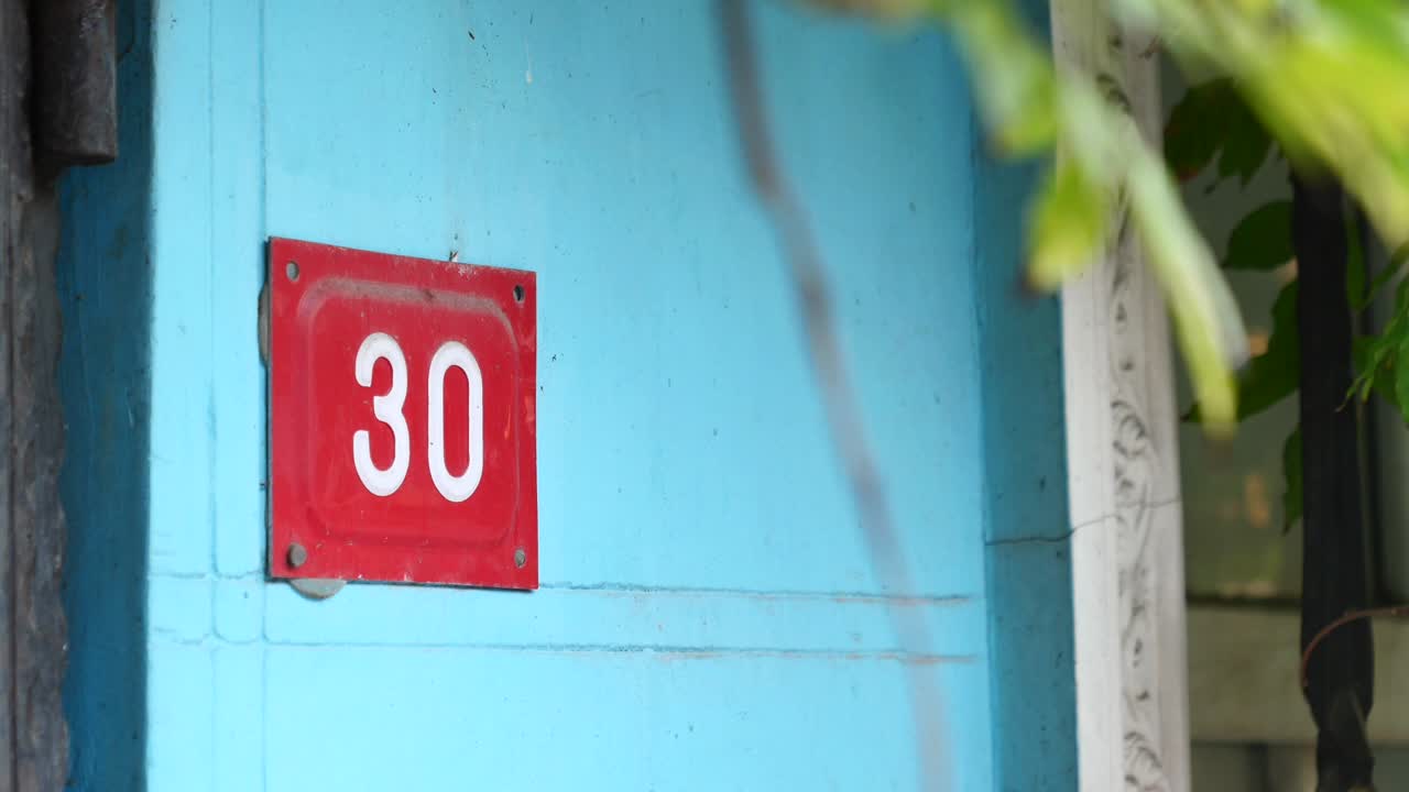 Número de casa 30 en una pared azul