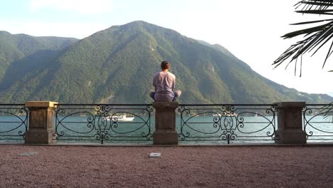 guy meditating on the lake with beautiful mountains and landscape