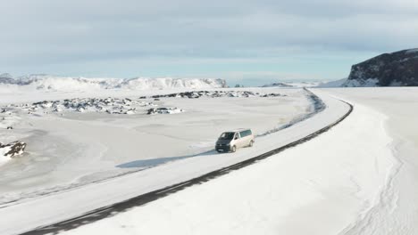 a tracking shot for a gray car traveling in the middle of the snow
