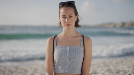 portrait of attractive young caucasian woman on beach looking confident at camera enjoying warm summer vacation day in ocean seaside background