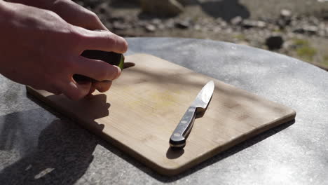 cortando un aguacate maduro en una tabla de cortar con un cuchillo y quitando el hoyo