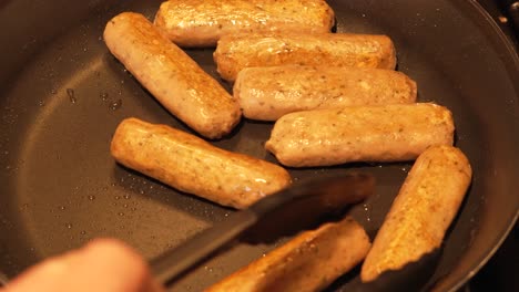 fake meat sausages cooking in hot frying pan being turned by chef