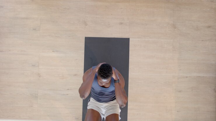 vista dall'alto focalizzata su un uomo afroamericano che fa crunches in un soggiorno soleggiato, in rallentatore
