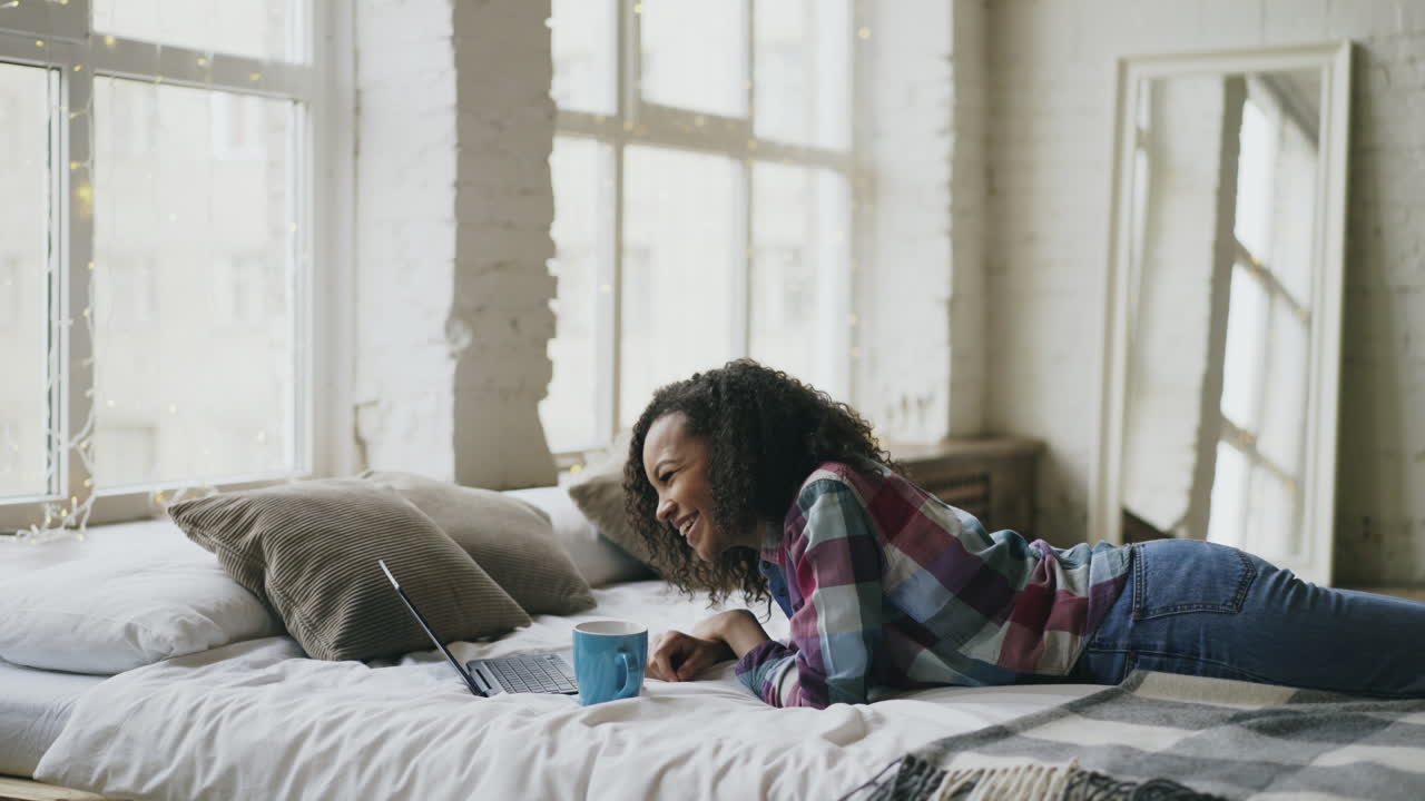 Teenager Relaxing on Bed with Laptop