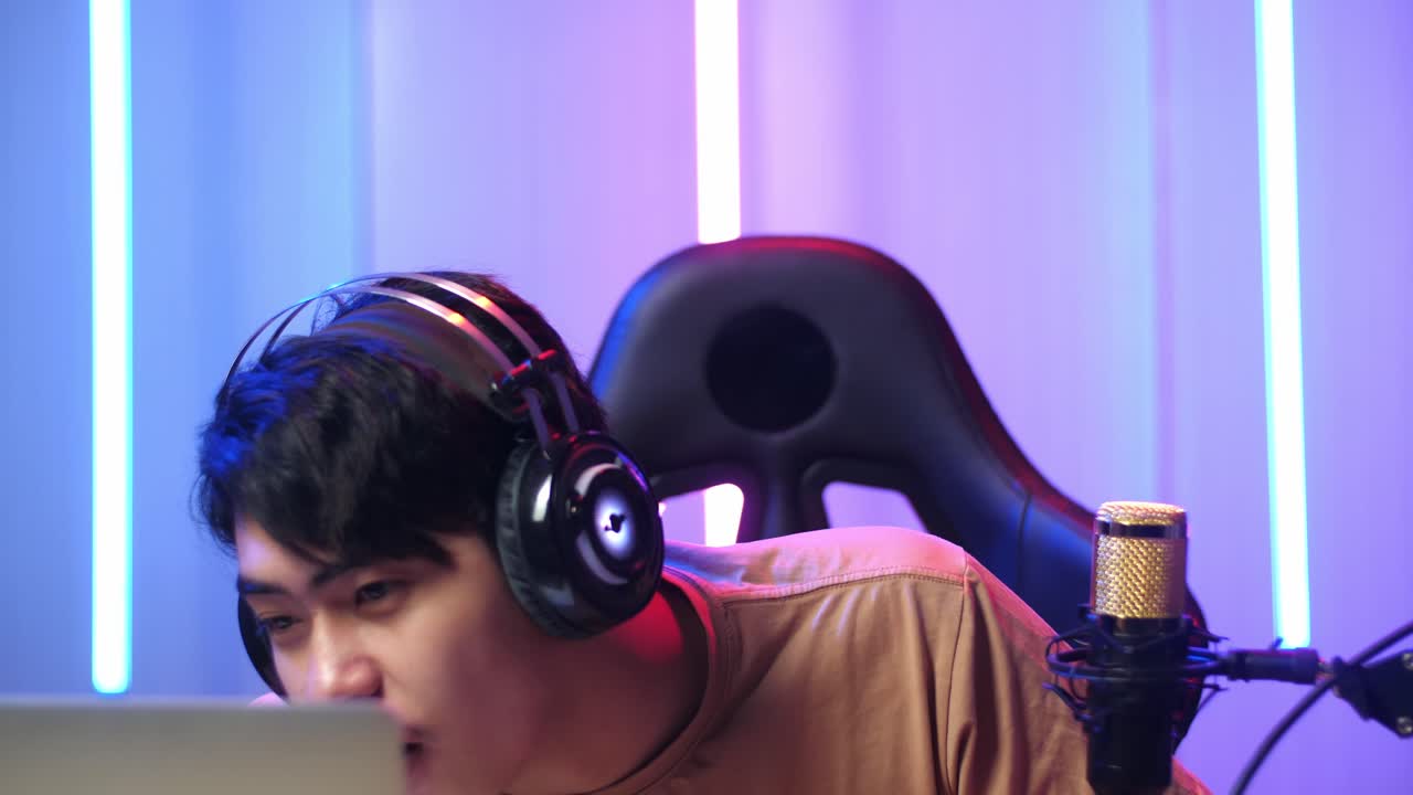 Asian Man Holding Mobile Phone And Read Comment In Laptop Computer Then Talking To Camera While Live Stream