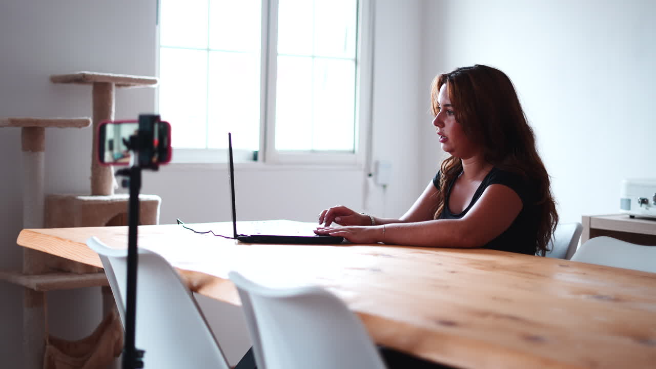 Mujer trabajando en un portátil en casa con una configuración de videollamada
