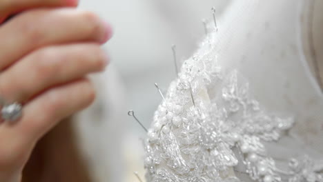 close-up fashion designer for brides in his studio pins needles lace wedding dress. seamstress creates an exclusive wedding dress. secure with pins and needles outline. small private business