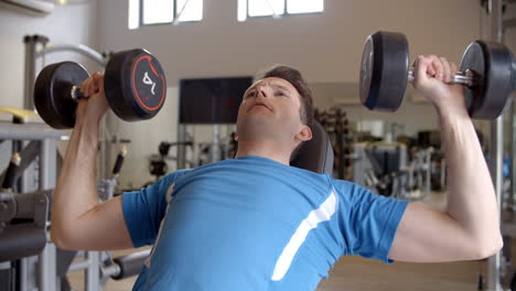 man works out with dumbbells on a bench at a gym, close up shot on r3d