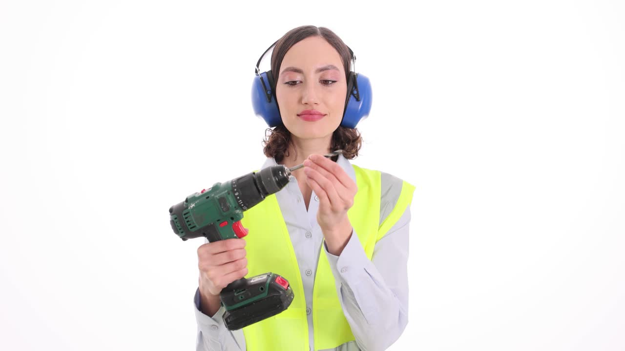 Woman in safety gear holding a power drill and a drill bit