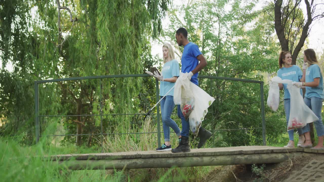 adultos de mediana edad voluntariando y caminando por un puente durante el día de limpieza del río