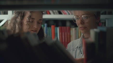 dos amigas discutiendo libros en el estante de la biblioteca pública